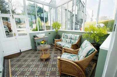 a porch with wicker chairs and a table at Acorn House in Keswick