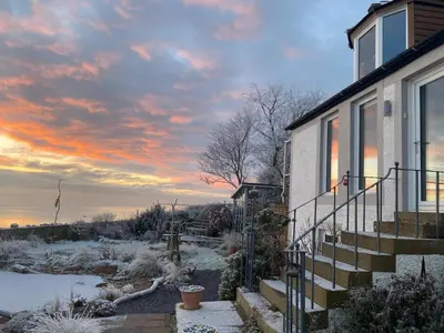 a house with a sunset in the background at The Waterside Rooms in Annan