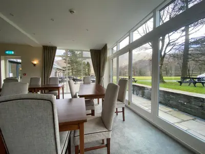 a dining room with tables and chairs and large windows at Glaramara Hotel in Borrowdale Valley