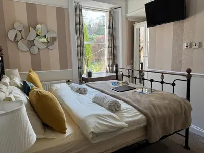 a bedroom with a large bed with a window at Buchan Guest House in Moffat
