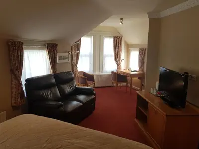 a hotel room with a bed and a couch and a television at Welbeck Hotel & Apartments IOM in Douglas