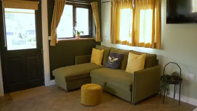 a living room with a green couch and windows at Glen Wyllin Campsite in Kirkmichael