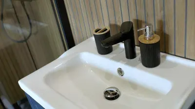 a white bathroom sink with a black faucet at Glen Wyllin Campsite in Kirkmichael