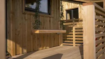 a wooden deck with a bench on the side of a building at Glen Wyllin Campsite in Kirkmichael