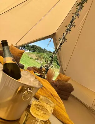 a bottle of wine in a bucket in a tent at Glen Wyllin Campsite in Kirkmichael
