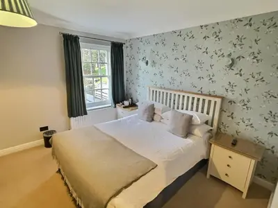 a bedroom with a bed with white sheets and floral wallpaper at Three Shires Inn in Little Langdale