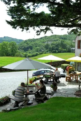 a group of people sitting at tables with umbrellas at Three Shires Inn in Little Langdale