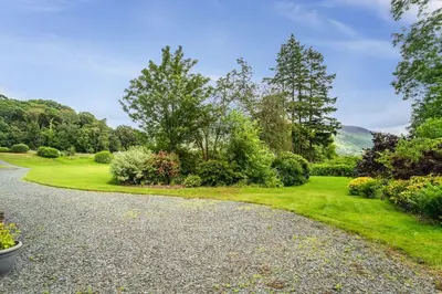 a gravel road in a garden with trees and bushes at Lords Seat in Keswick