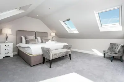 a bedroom with a bed and a chair and windows at The Alexander - Donnini Deluxe in Prestwick