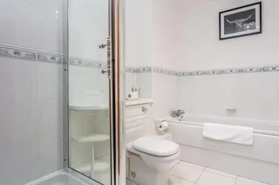 a white bathroom with a toilet and a shower at Turnberry Serviced Apartments in Turnberry