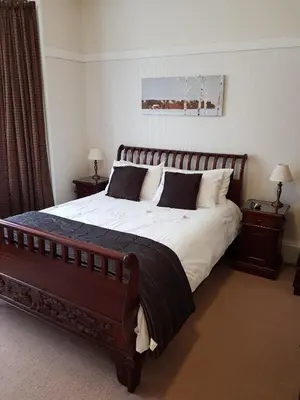 a bedroom with a large bed with two nightstands and two lamps at Hamilton House in Dumfries