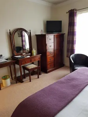 a bedroom with a dresser and a mirror and a desk at Hamilton House in Dumfries