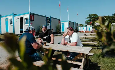 a group of people sitting at a picnic table at IOMTT Village at Isle of Man TT in Douglas