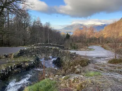 a stone bridge over a river in the mountains at Crow Park Hotel in Keswick