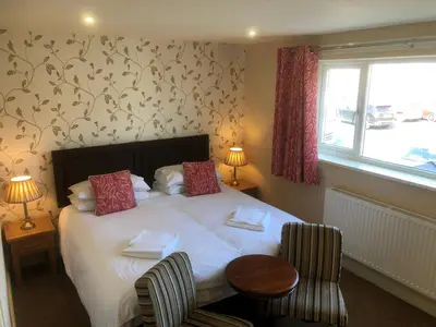 a bedroom with a bed with two chairs and a window at Crow Park Hotel in Keswick