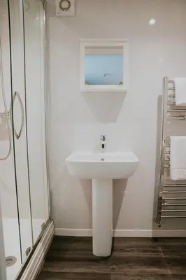 a white bathroom with a sink and a shower at Crossroads House in Carlisle