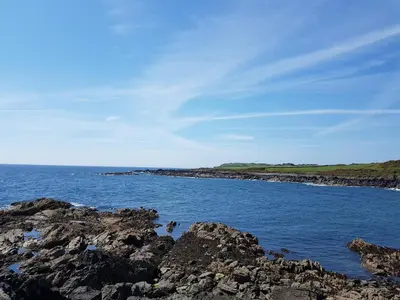 a large body of water with rocks in the foreground at 11 Laigh Isle in Isle of Whithorn