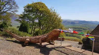 a statue of a dinosaur sitting on top of a hill at Windsor Cottage on The Big 