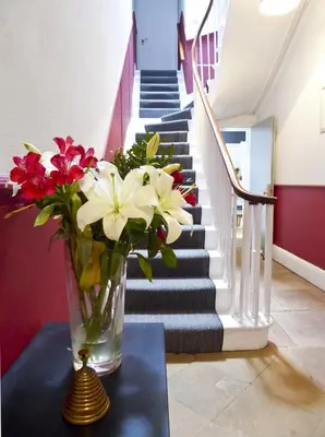 a vase of flowers sitting on a table with stairs at Rosalind House in Carlisle