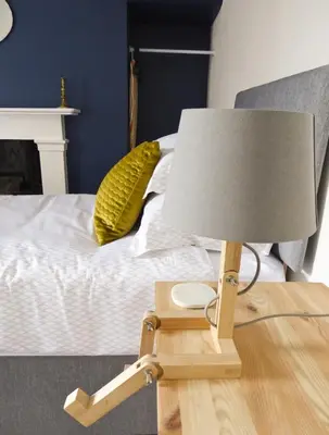 a lamp on a wooden table next to a bed at Rosalind House in Carlisle