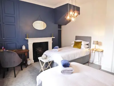 a blue bedroom with two beds and a fireplace at Rosalind House in Carlisle