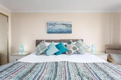 a bedroom with a large bed with blue pillows at Arran View - Coorie Doon Stays in Ayr