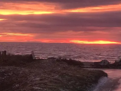 a sunset over the ocean with the sky at Dove cottage in Allonby