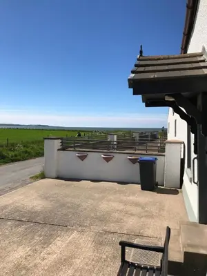 a bench on a building with a view of the ocean at Sea view cottage in Allonby