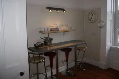 a bar in a room with stools and a clock at Mid Flat in Dumfries