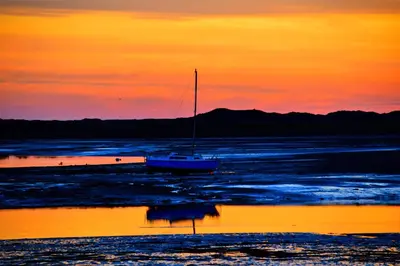 a sail boat sitting in the water at sunset at OLD BAKEHOUSE in Holmrook