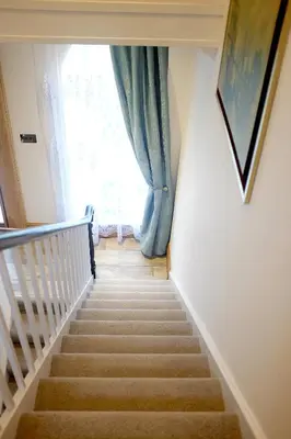 a staircase with a blue curtain and a window at Welch House in Douglas