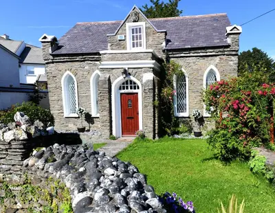 a church with a red door and a yard with rocks at Welch House in Douglas