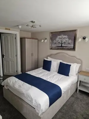 a bedroom with a large bed with blue and white pillows at Fairladies Barn Guest House in St Bees