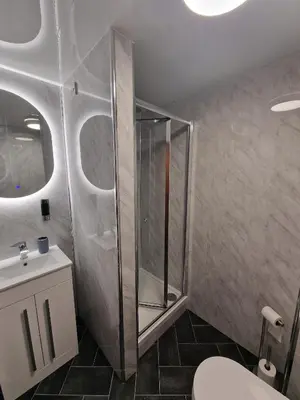 a bathroom with a shower and a toilet and a sink at Fairladies Barn Guest House in St Bees