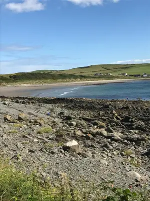 a beach with rocks and the ocean in the background at Cornmill House, With Outstanding Sea Views In Garlieston in Garlieston