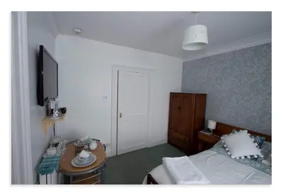a bedroom with a bed and a desk and a television at Cornmill House, With Outstanding Sea Views In Garlieston in Garlieston