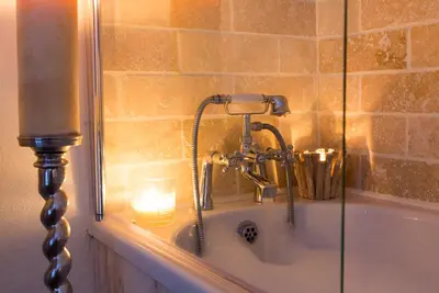 a bathroom with a bath tub with a candle in it at The Nook Cottage in Carlisle