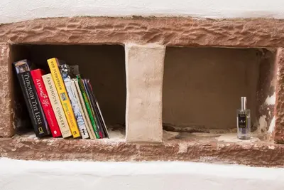 a book shelf with a bunch of books and a glass at The Nook Cottage in Carlisle