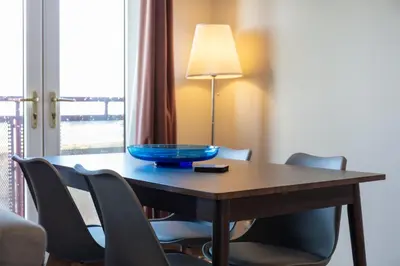 a wooden table with chairs and a blue bowl on it at Bay View - Donnini Apartments in Ayr