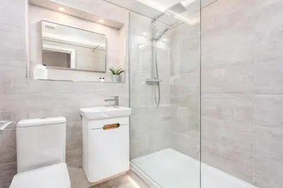 a bathroom with a toilet and a glass shower at Bay View - Donnini Apartments in Ayr