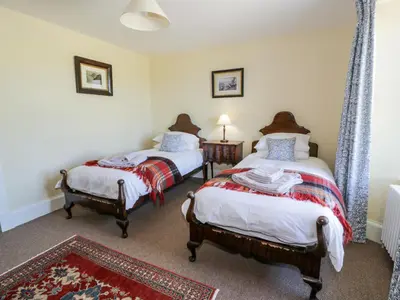 a bedroom with two beds and a rug at Marl House in Newton Stewart