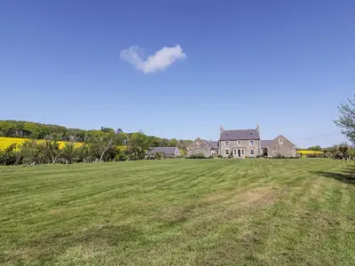 a large field with a house in the background at Marl House in Newton Stewart