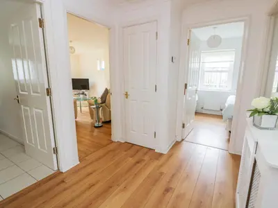 a hallway with white walls and a hard wood floor at Bright and Beautiful in Ayr