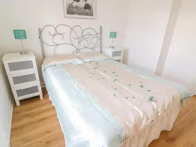a bed in a bedroom with two night stands and two lamps at Bright and Beautiful in Ayr