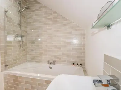a white bathroom with a tub and a sink at Coney Garth Cottage in Beckermet