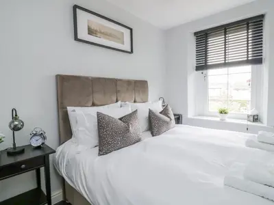 a bedroom with a white bed with pillows and a window at 8 Bridge Street in Cockermouth
