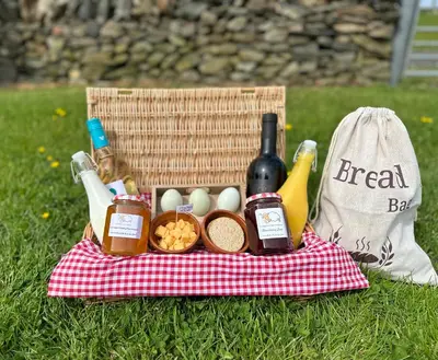 a picnic basket with a basket of food and wine at Lodge Cabin with Fabulous Views - Farm Holiday in Stranraer