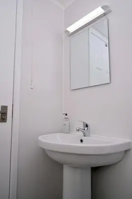 a white bathroom with a sink and a mirror at Lodge Cabin with Fabulous Views - Farm Holiday in Stranraer