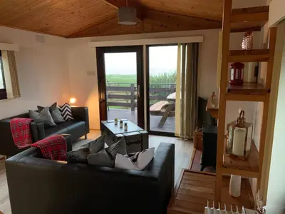 a living room with a couch and a table at Lodge Cabin with Fabulous Views - Farm Holiday in Stranraer