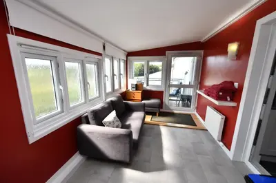 a living room with red walls and a couch and windows at Lochans Lodge in Stranraer